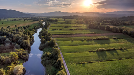 Aerial view of river bending across fields at sunset.