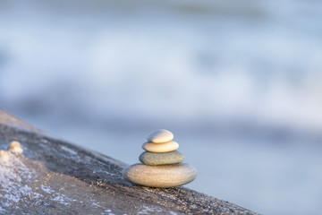 Sunlight shining on four smooth beach stones stacked and balanced