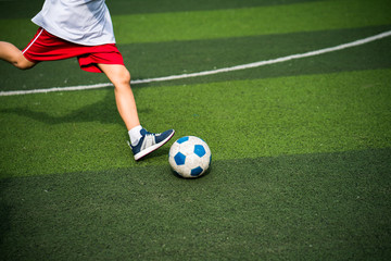 Boy legs kicking football ball closeup