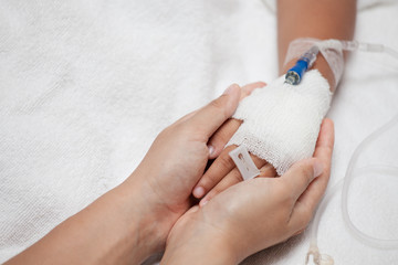 Mother hand holding child hand who have IV solution in the hospital with love and care