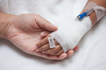Mother hand holding child hand who have IV solution in heart shape in the hospital with love and care