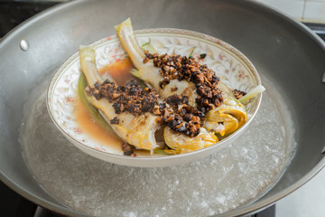 steaming a fresh fish on a pot at home