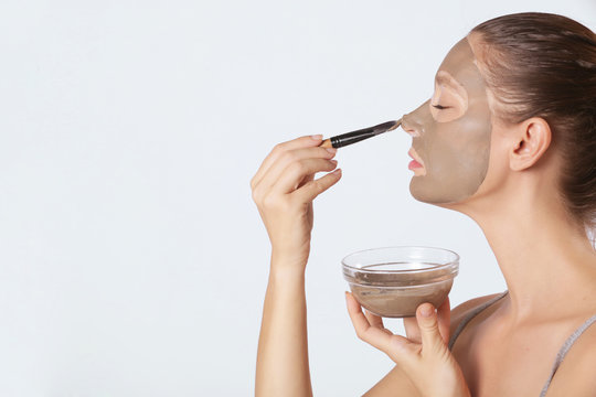 Young Woman Applaying Green Face Mask - Studio Portrait