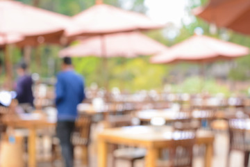 Blurred image as background of outdoor restaurant with tables, chairs & parasols