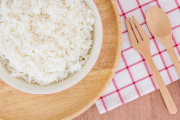 closed up of bowl full of rice in plate and spoon on wooden table