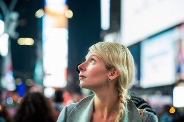 Naklejka premium Impressed Woman in the Middle of Times Square at Night,