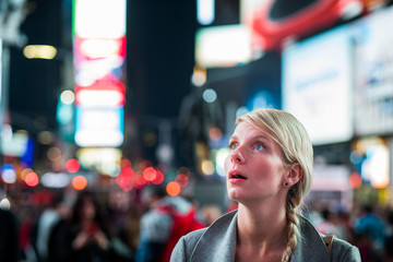 Naklejka premium Impressed Woman in the Middle of Times Square at Night,