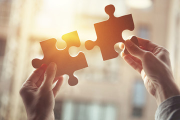 Businesswoman hand connecting jigsaw puzzle with sunlight effect, Business solutions, success and strategy concept. - obrazy, fototapety, plakaty