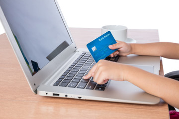 Child's hands holding credit card and typing on keyboard