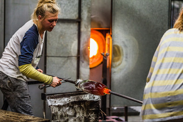 Two Blowing Glass Artists Finishing a Piece.