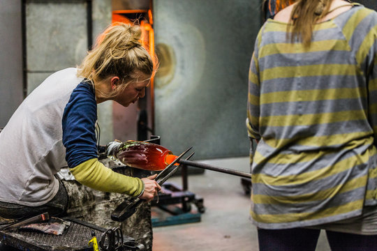 Two Blowing Glass Artists Finishing a Piece.
