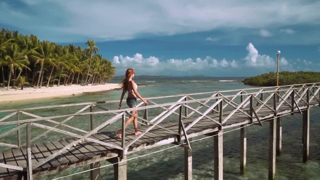 Young woman walking on boardwalk in ocean close to tropical island - Cloud 9 boardwalk on Siargao Island, Philippines