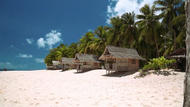 Small bungalows on white sand beach on tropical island, volleyball net - Daku Island, Philippines