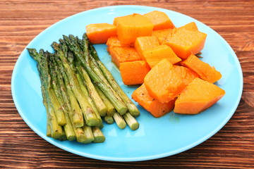Baked asparagus pumpkin on plate on wooden background
