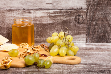 Cheese, grape, nuts and honey on wooden background in studio photo