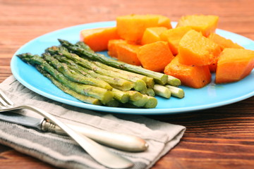 Baked asparagus pumpkin on plate on wooden background