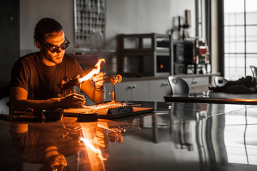Glassblowing Young Man Working on a Torch Flame with Glass Tubes