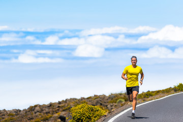 Sports man running on road training for marathon in nature landscape outdoors.