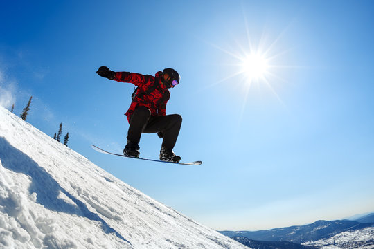 Snowboarder jumping from the springboard against the sky