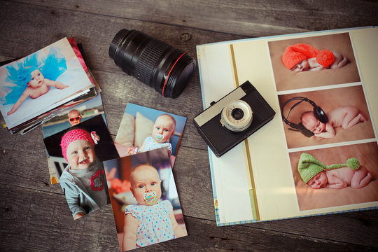 Album with children is photos, the ancient camera and a lens on a wooden background