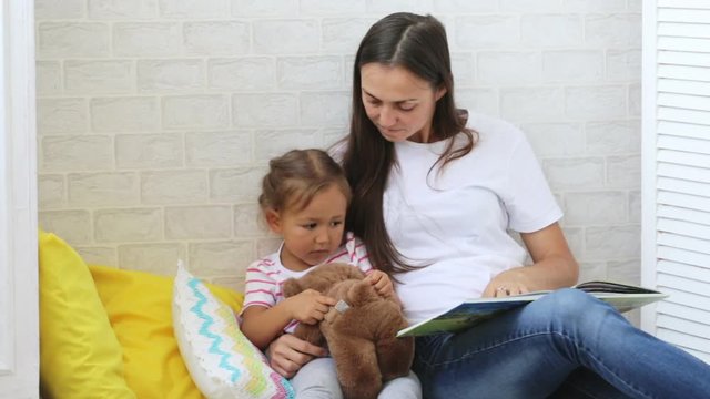 Young mother reading book for her little daughter.