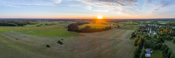 Beautiful sunset over the small town. Fields and trees around. Aerial photography panorama.