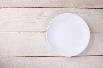 Top view of empty white plate put on white wood table with space for copy.