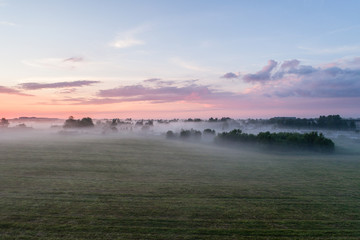 Fototapeta na wymiar Aerial view of fields with fog at amazing sunset. Summer nature landscape.