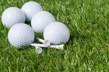 White golf balls lie on a heap of green grass