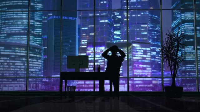 Silhouette of a man working late in the office at the computer