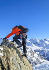 erfahrener Kletterer an einer steilen Felswand im winterlichen Hochgebirge