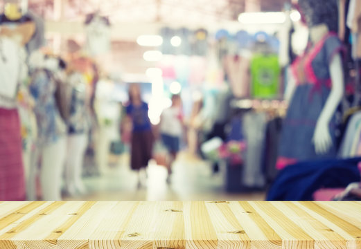 Blurred image of retail store in shopping mall montage with wood table for background.