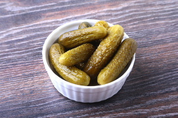 Bowl with pickled gherkins, cucumbers on wooden background close up. Pickles.
