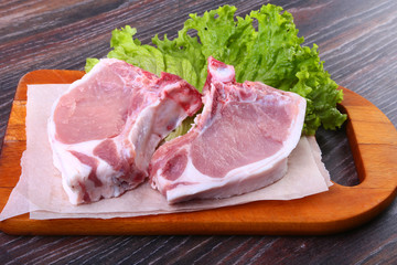 Raw pork steak with spices Leaves lettuce on wooden cutting board. Ready for cooking.