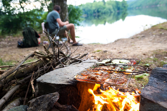 Fisherman preparing dinner on campfire, adventure lifestyle camping fishing vacation concept