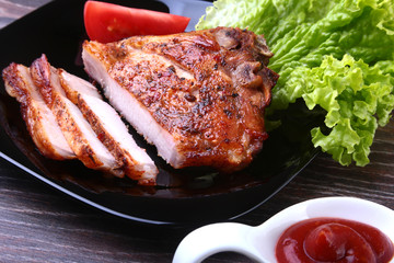 grilled pork chops with tomato, leaves lettuce and ketchup on plate.