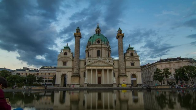 Sunset timelapse of Karlskirche (Church) at Karlsplatz in Vienna/Austria first district (old town) with reflection in the fountain in front of the picture; Beautiful moving clouds and light in 4K
