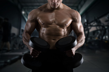 Fototapeta na wymiar Athletic man training biceps at the gym