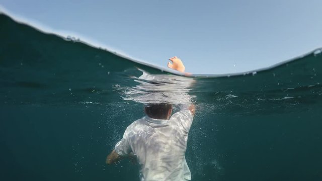 man sinking into the sea, half underwater close up, raw, 4k
