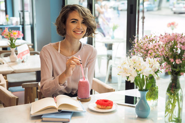 Smiling pretty girl drinking smoothie with a straw