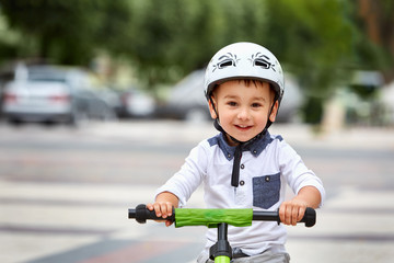 Obraz premium Little boy kid in helmet ride a bike in city park. Cheerful child outdoor.