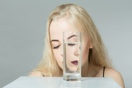 sad girl closed eyes glass with water on gray background