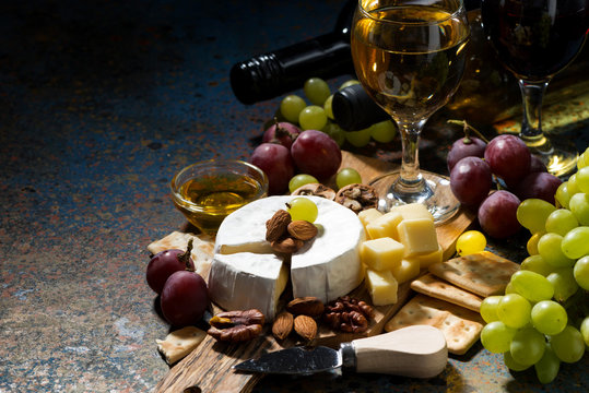 snacks, wine and Camembert cheese on a dark background