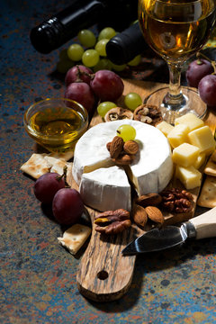 snacks, wine and Camembert cheese on a dark background, vertical, top view