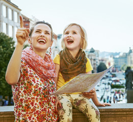 mother and child travellers in Prague holding map and pointing