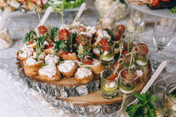 Italian antipasti wine snacks set. Brushettas, cheese variety, Mediterranean olives, pickles, Prosciutto di Parma with melon, salami and wine in glasses over black grunge background, top view