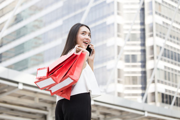 woman holding red shopping bag with attractive smile at city.