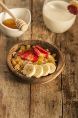 oatmeal porridge with strawberry and banana in wood bowl
