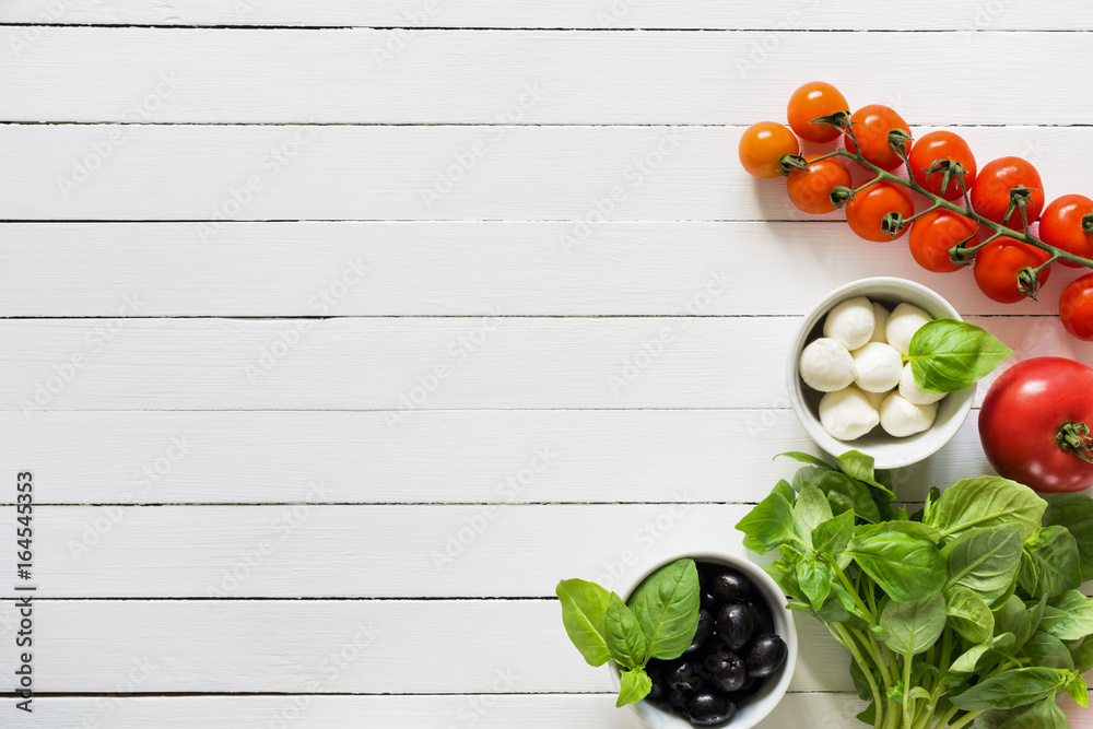 Wall mural fresh food ingredients for italian cuisine. bunch of green basil, black olives, mozzarella cheese an