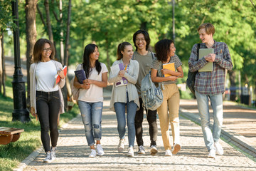 Happy young students walking outdoors - obrazy, fototapety, plakaty